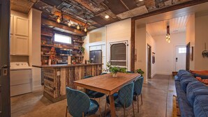 Una cocina de estilo rústico, con paredes de ladrillo visto, una mesa de madera y sillas azules.