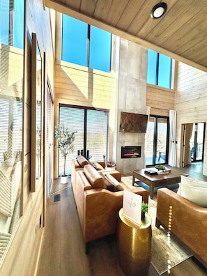 A spacious living area with a large sofa, a coffee table, and a fireplace. - Mountain High Rooftop Cabin Pigeon Forge NEW Indoor Pool Hot Tub Sleeps 15 (Pigeon Forge)