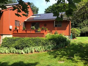 Um edifício vermelho com telhado solar, área de jardim cercada e um gramado bem cuidado.