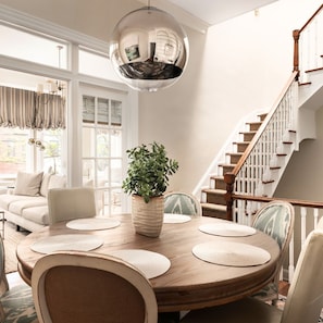A dining area with a round table, chairs, a potted plant, and a staircase. - Charming 4-Bedroom Home in Historic Old Town - minutes from King St, DC, & Metro (Alexandria)