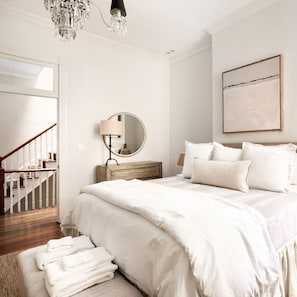 A bedroom with a bed, a chandelier, a mirror, and a staircase. - Charming 4-Bedroom Home in Historic Old Town - minutes from King St, DC, & Metro (Alexandria)