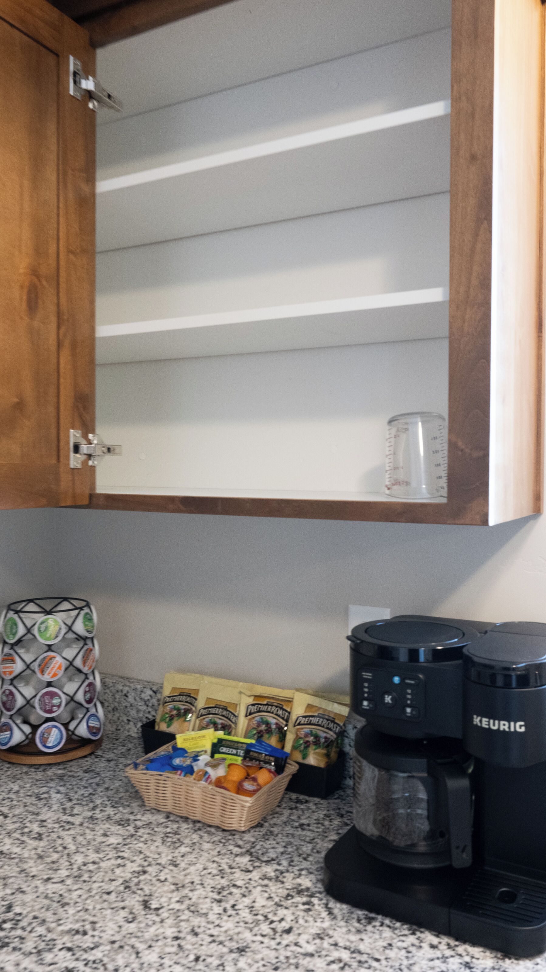 A kitchen with a coffee maker, a basket of coffee pods, and a bag of coffee beans.