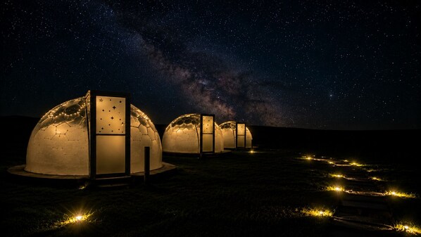 A series of dome-shaped structures with illuminated interiors, set against a starry night sky.