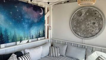 A cozy seating area with a starry night mural, a round moon-like wall decoration, and a wooden pendant light.