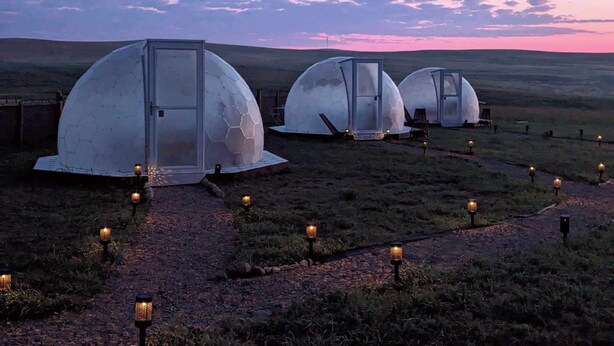 Three dome-shaped structures with glass doors, connected by a gravel path with lanterns, set against a twilight sky. - Meadowlark Sky Domes - Sleeps 6 + Private Hot Tub +Cold Plunge Pool! (Cardston)