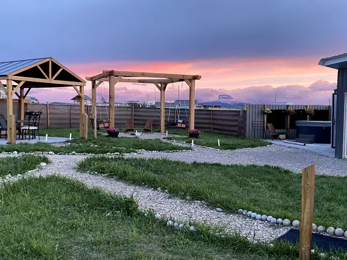 A backyard with a wooden pergola, seating area, and a hot tub.