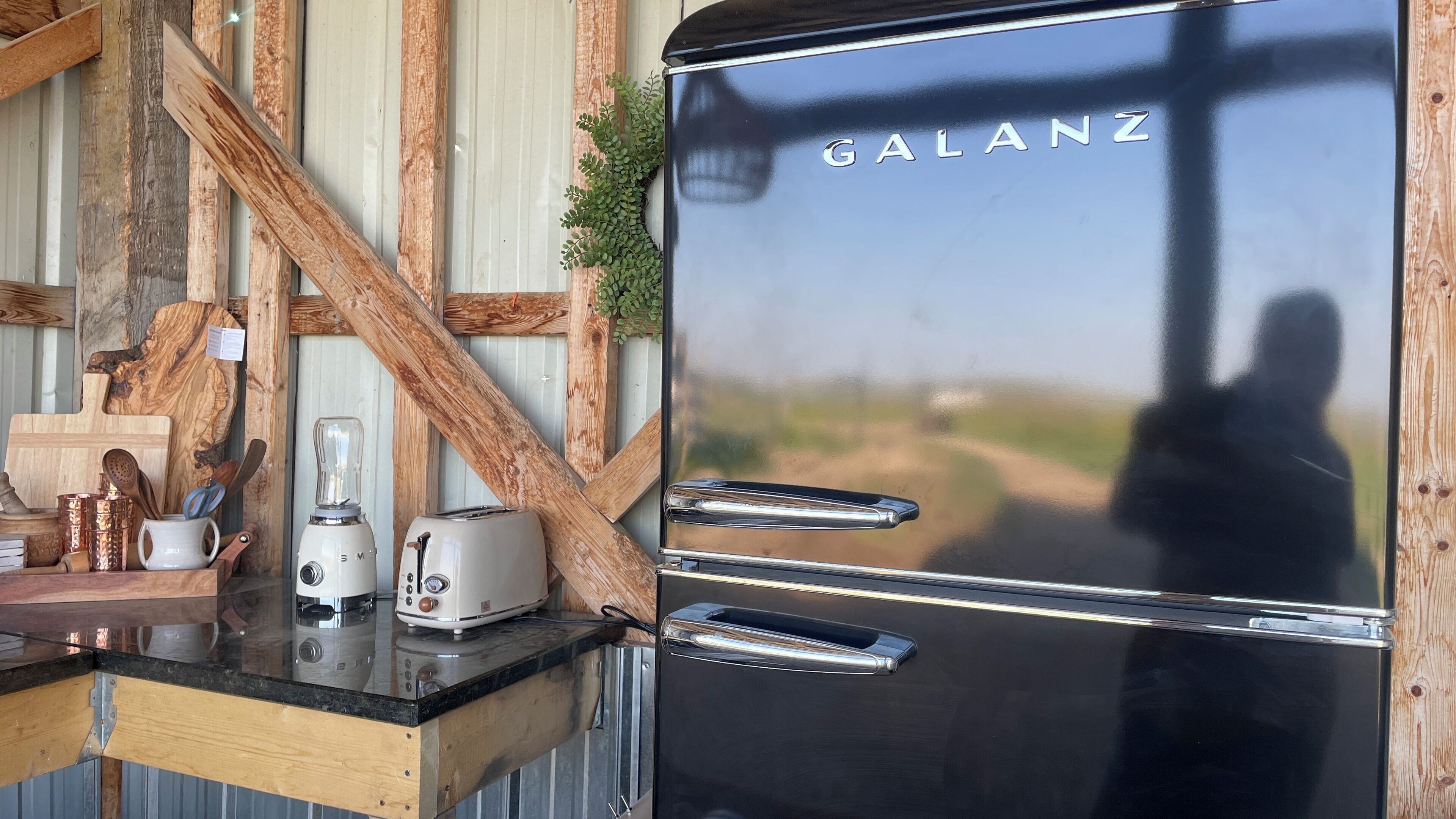 A kitchen with a Galanz refrigerator, a blender, a toaster, and wooden utensils on a counter.