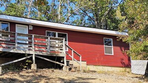 Une cabane en bois rouge avec un escalier en bois menant à une terrasse.