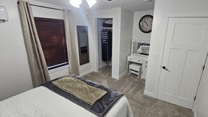 Une chambre à coucher avec un lit, une armoire, un miroir et une horloge au mur.