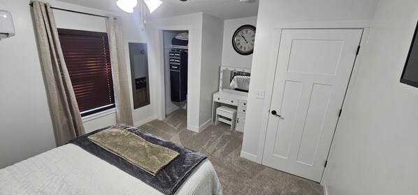 A bedroom with a bed, a wardrobe, a mirror, and a clock on the wall.