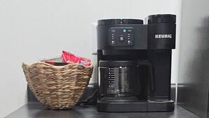 Une petite cuisine équipée d’une machine à café, d’un panier et d’un meuble en bois.