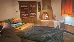 A cozy living room with a fireplace, a sofa, a coffee table, and a TV stand. - Cozy Private Adobe Studio • Kiva Fireplace • Walk to Taos Plaza • Pet-Friendly (Taos)