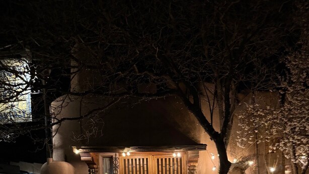 A building with a wooden door and a small porch area. - Cozy Private Adobe Studio • Kiva Fireplace • Walk to Taos Plaza • Pet-Friendly (Taos)