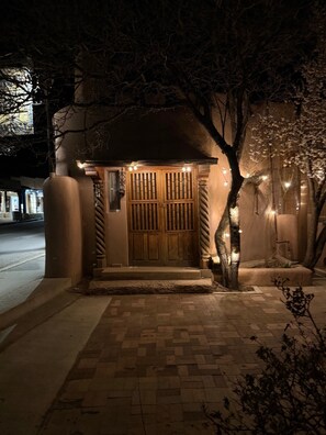 A building with a wooden door and a small porch area. - Cozy Private Adobe Studio • Kiva Fireplace • Walk to Taos Plaza • Pet-Friendly (Taos)