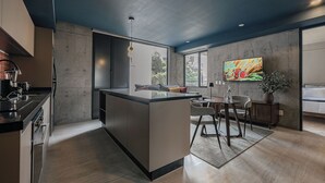 A modern kitchen with a central island, dining area with chairs, and a large TV on the wall. - Indigo Veracruz Roma norte Apt 1B I 1B (Mexico City)
