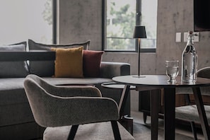 Una sala de estar moderna con un sofá gris, una mesa redonda y una botella.