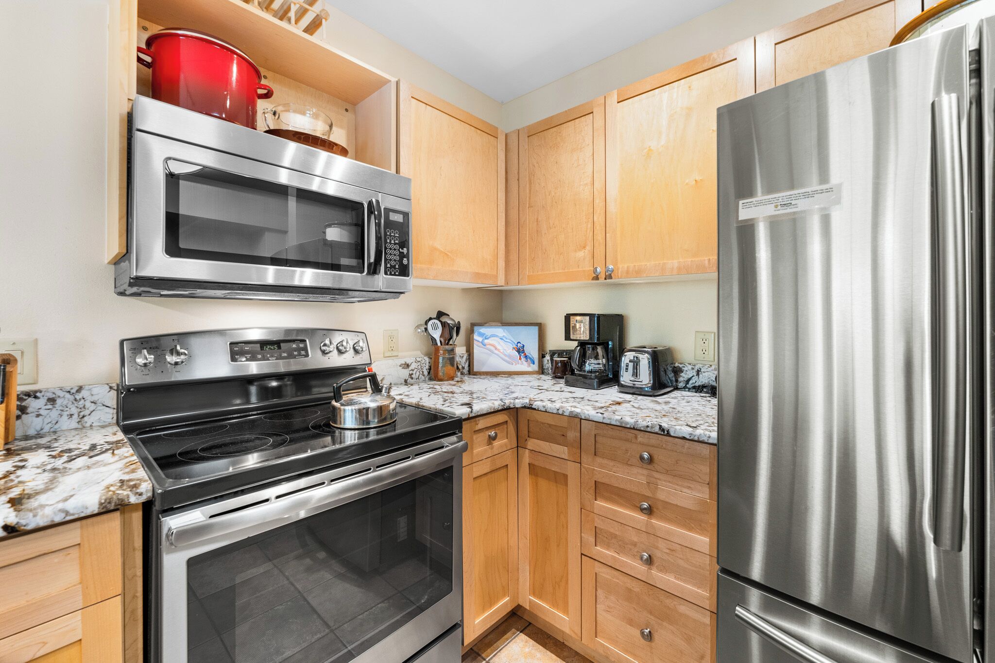 A kitchen with stainless steel appliances, wooden cabinets, and a granite countertop.