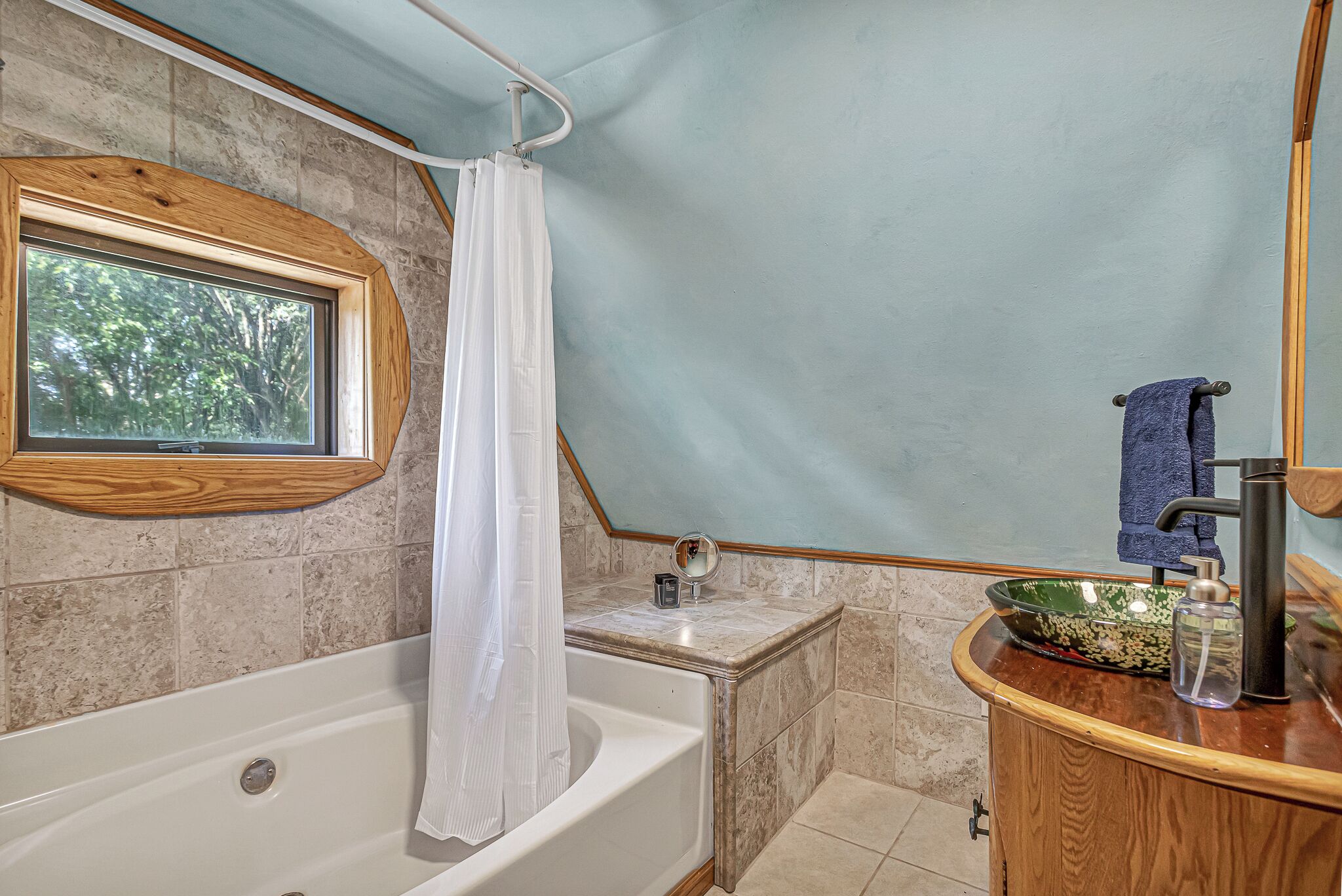 Une salle de bain avec une baignoire, un lavabo avec un miroir et une fenêtre.