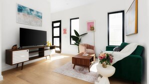 A modern living room with a flat-screen TV, wooden entertainment unit, green sofa, and a coffee table. - Modern East Austin Hideaway - Stylish - Walkable (Austin)