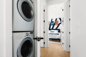 A laundry room with two washing machines and a bedroom with a bed and a painting on the wall. - Modern East Austin Hideaway - Stylish - Walkable (Austin)