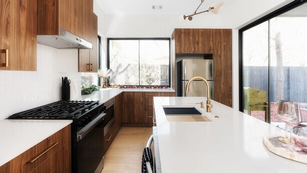 A modern kitchen with wooden cabinets, a stainless steel stove, and a large window. - Modern East Austin Hideaway - Stylish - Walkable (Austin)