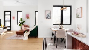 A modern living room with a dining area, featuring a sofa, a coffee table, and a dining table with chairs. - Modern East Austin Hideaway - Stylish - Walkable (Austin)