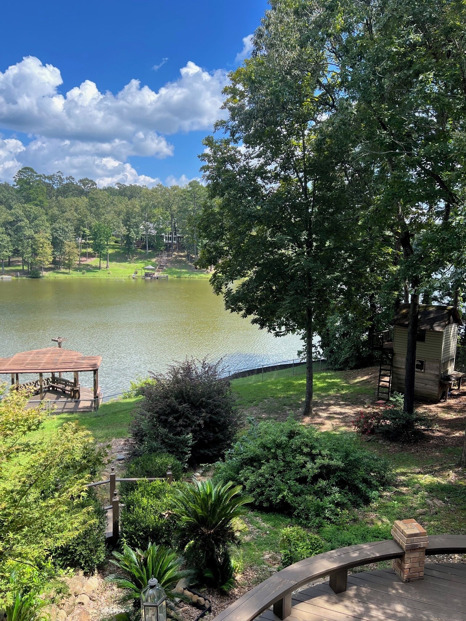 A lakeside view with a wooden dock, a gazebo, and a small cabin.