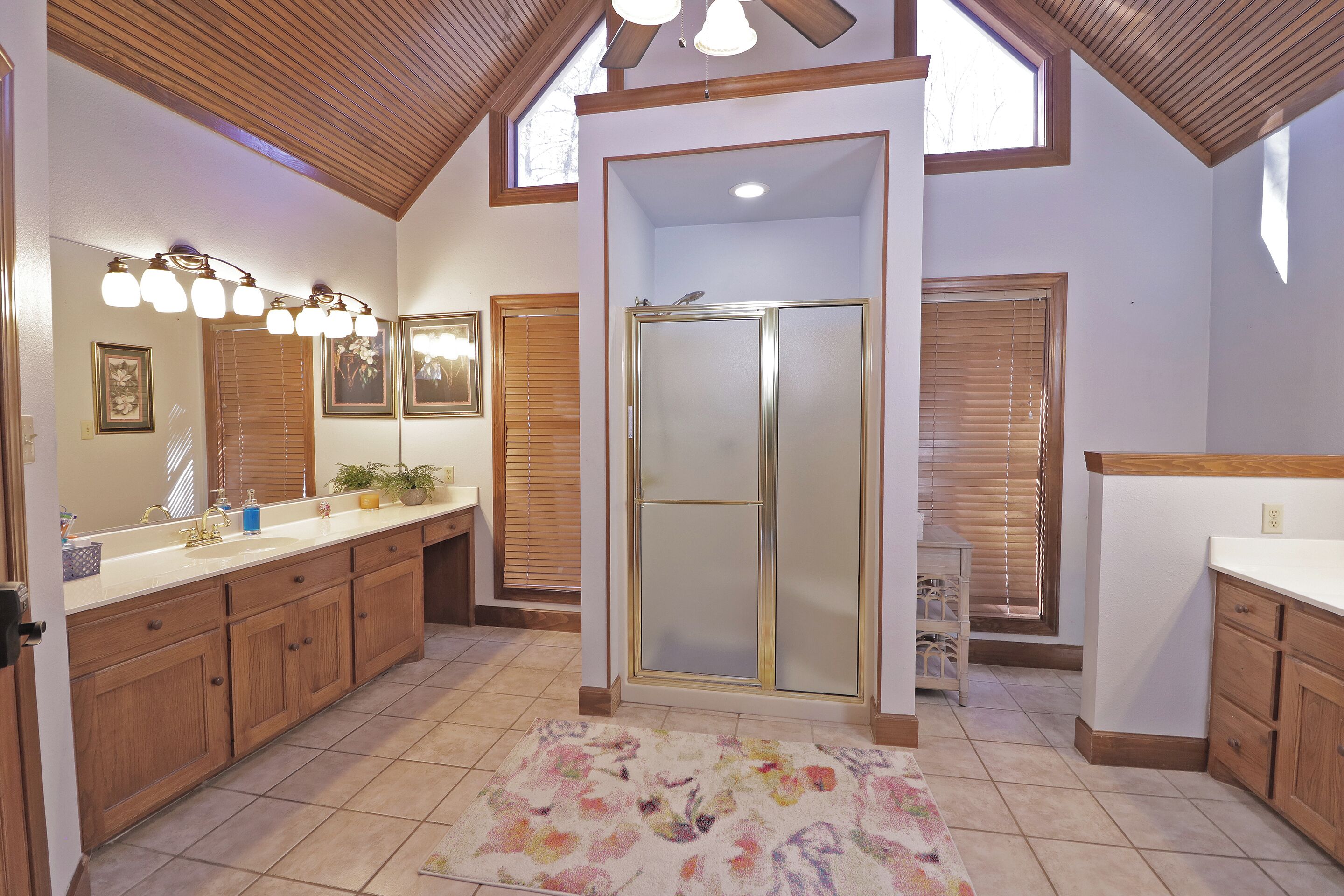 A spacious bathroom with a large vanity, a shower enclosure, and a skylight.
