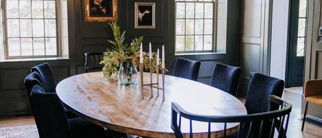 A dining room with a round table, black upholstered chairs, a chandelier, and framed artwork on the walls.
