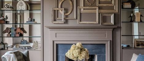 A living room with a fireplace, a chandelier, and a coffee table with decorative items.
