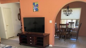 Un saló amb televisió plana, un moble d'entreteniment de fusta i una zona de menjador amb un penjoll.