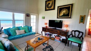 A living room with a sofa, a coffee table, a TV, and framed pictures on the wall.