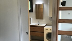 A compact bathroom with a sink, mirror, and washing machine.