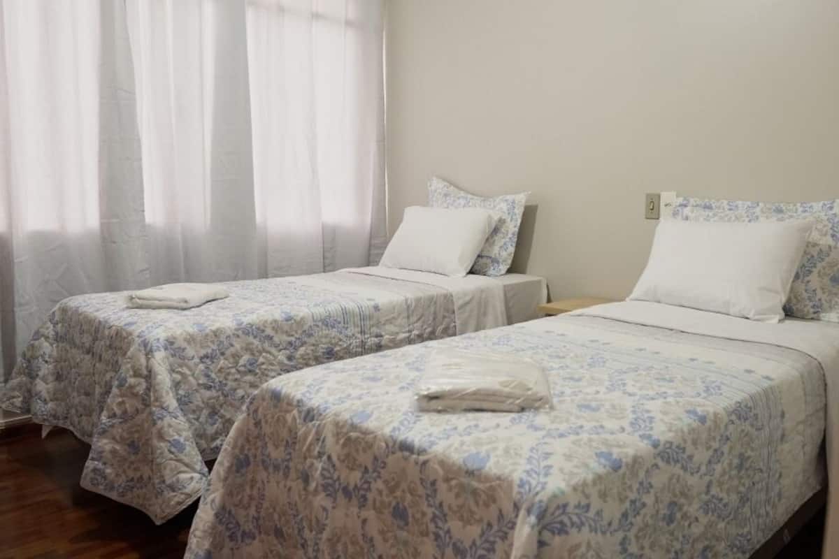 A room with two beds, each with a floral-patterned bedspread and white pillows.