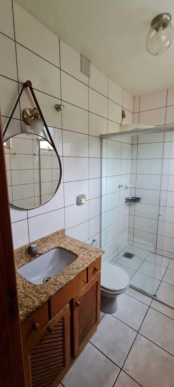 Un baño con lavamanos, espejo, inodoro y cabina de ducha de vidrio.