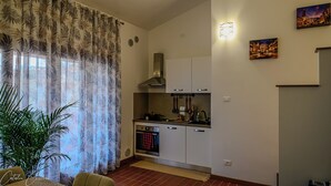 Una cocina compacta con armarios blancos, una estufa y un colgador para ollas.
