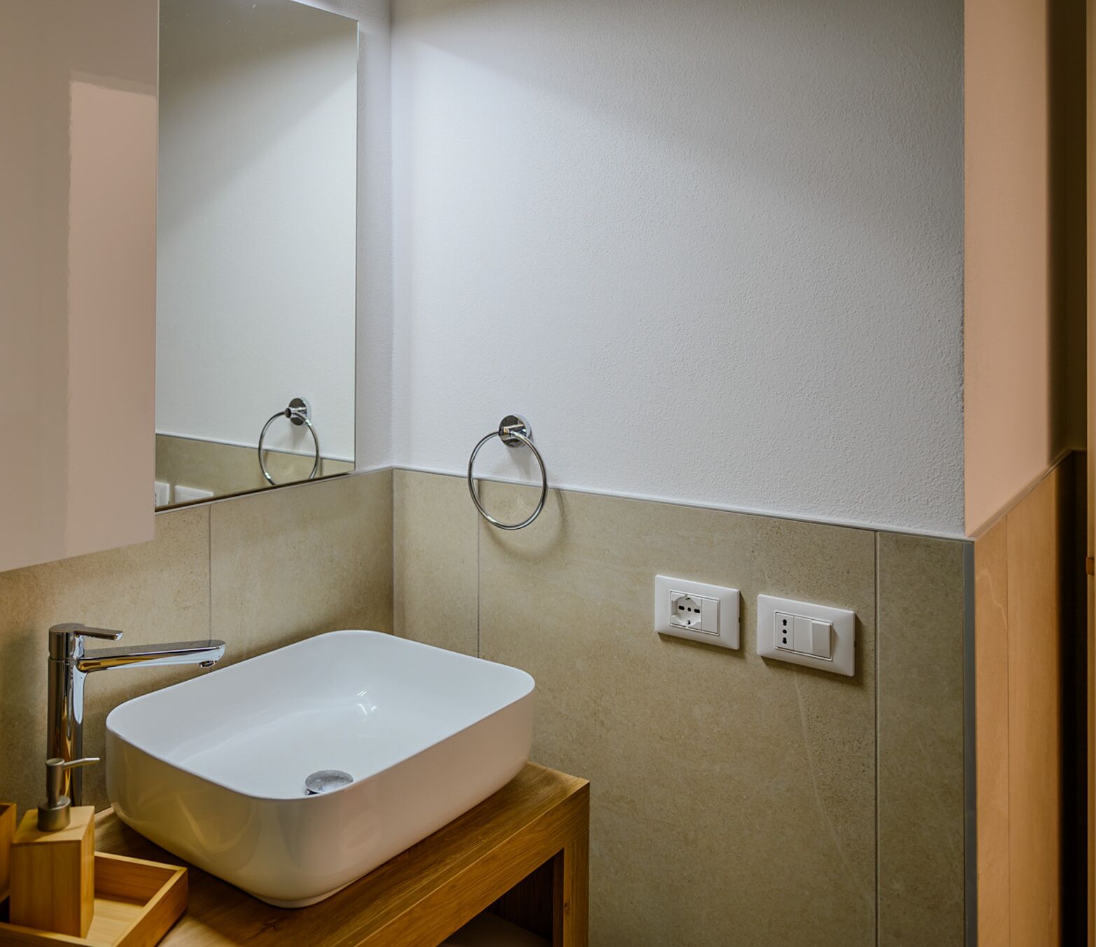 A bathroom with a white sink, a mirror, and two wall-mounted light switches.