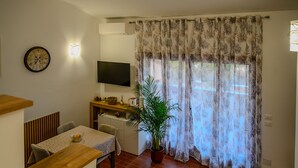 Un comedor con una mesa y sillas de madera, una planta en maceta y un televisor en la pared.