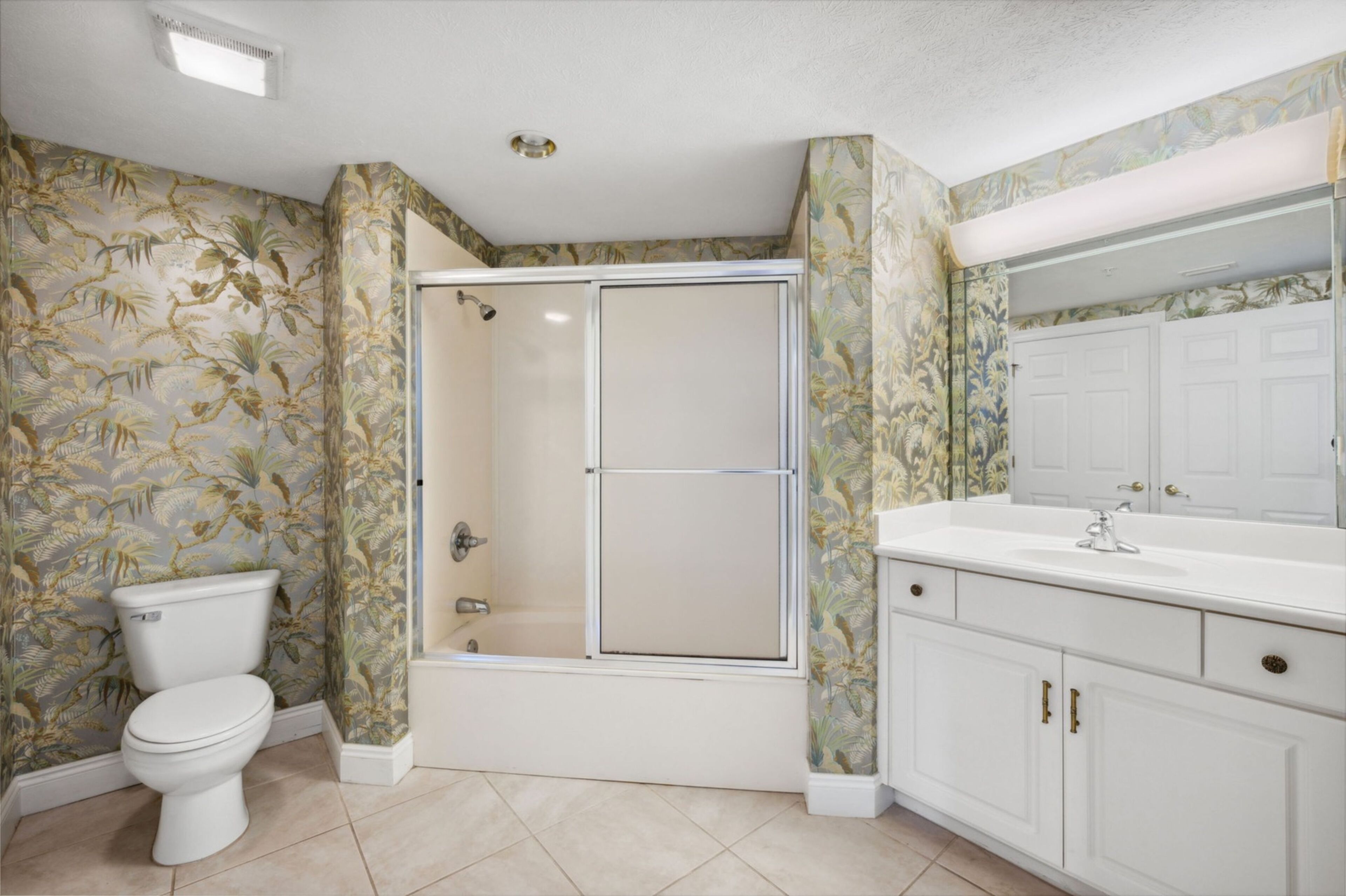 A bathroom with a toilet, shower, and sink.
