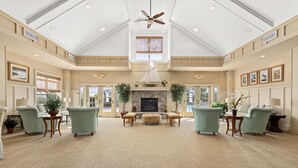 A spacious lobby with a high ceiling, a fireplace, and a large window.
