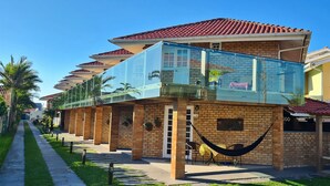 Een rij bakstenen huizen met een glazen balkon, een hangmat en een patio.
