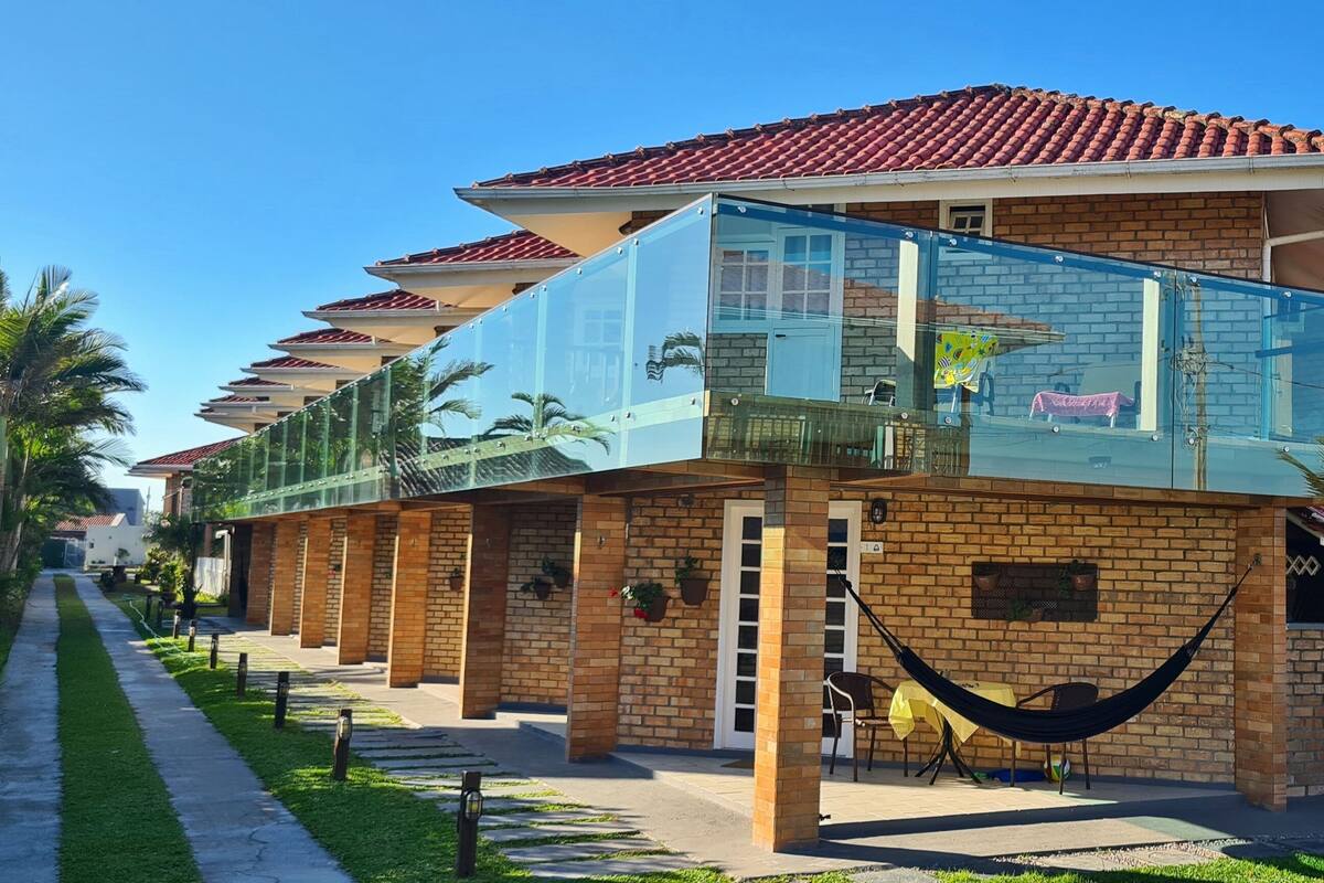 A row of brick houses with a glass balcony, a hammock, and a patio area.