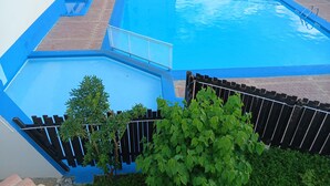 Une piscine rectangulaire bordée de bleu, avec une piscine plus petite à côté.