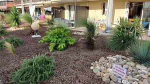 Une cour intérieure agrémentée de diverses plantes, un panneau indiquant une zone où la végétation est interdite, et un bâtiment doté de balcons.