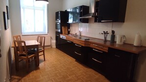 A compact kitchen with a wooden table and chairs, a built-in oven, and a window providing natural light.