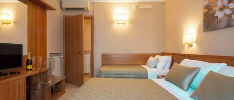 Una habitación de hotel con cama, mesita de noche, televisor y una silla transparente.