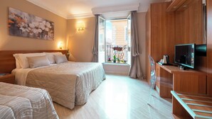 A hotel room with two beds, a TV, a desk, and a window with a view of buildings. - HOTEL MAGIC (Rome)