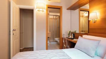 Ein Hotelzimmer mit Bett, Nachttisch, Lampe und Spiegel.