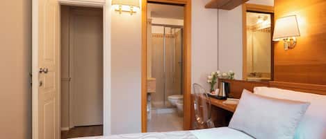 A hotel room with a bed, bedside table, lamp, and a mirror.