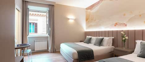 Una habitación de hotel con una cama grande, una mesita de noche, una silla, una pequeña mesa y un ventanal con cortinas.